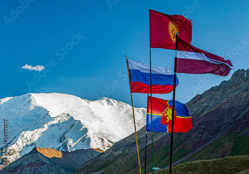 Beautiful nature. Scenic landscape of snowy mountain peaks. Waving flags of Latvia, Russia, Kyrgyzstan.