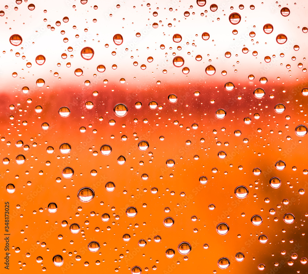 red rain water drops on a window glass close up , colored drop macro in a orange light ; ginger textute background red rain water drops on a window glass close up , colored drop macro in a orange light ; ginger textute background