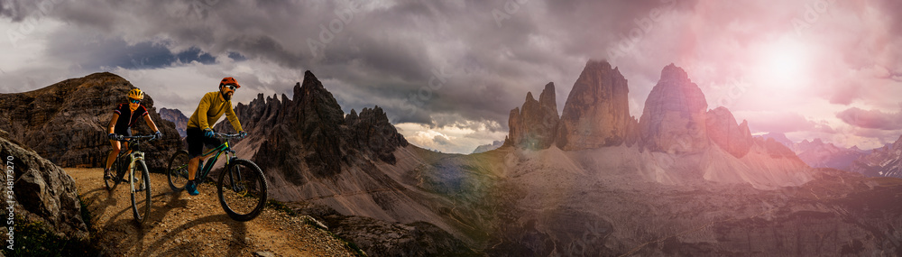 Cycling outdoor adventure in Dolomites. Cycling woman and man on electric mountain bikes in Dolomites landscape. Couple cycling MTB enduro trail track. Outdoor sport activity.