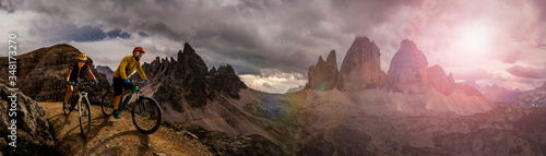 Obraz na płótnie Cycling outdoor adventure in Dolomites. Cycling woman and man on electric mountain bikes in Dolomites landscape. Couple cycling MTB enduro trail track. Outdoor sport activity. w salonie