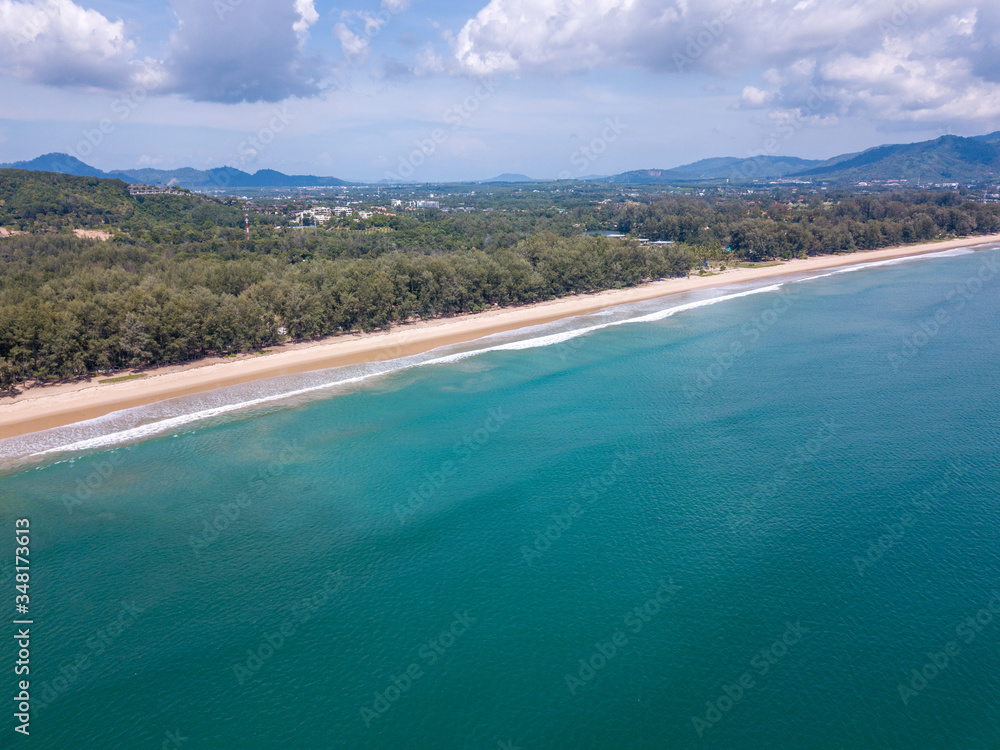 View from a high-angle drone of a beach in the northwest, against the community on the back of Phuket.