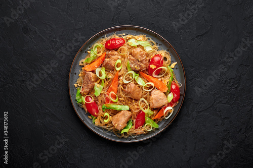 Pad Woon Sen or Thai Pork Glass Noodle Stir-Fry in black plate on dark slate backdrop. Pad Woon Sen is a Thai cuisine dish of glass bean noodles, meat, tomatoes, carrots, egg, sauces. Thai Food.