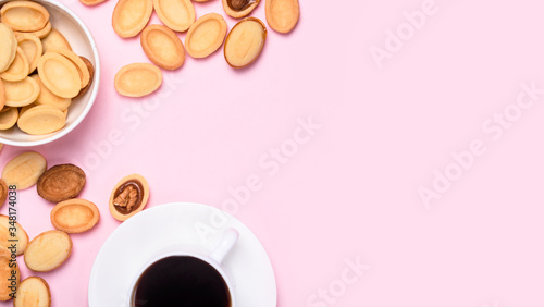 Homemade Russian nuts with condensed milk on a light pink background, wafer napkin. Cut nuts with condensed milk. Bitten goodies for coffee.