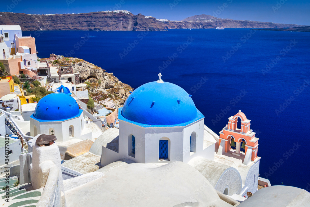 Naklejka premium Niebieskie kopuły kościoła i białe domy w pięknym mieście Oia na wyspie Santorini, Grecja.