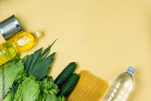 Essential fresh products lie on a yellow background. Greens food. Food delivery covid-19 epidemic, Donation. Top view. Copy space. photo