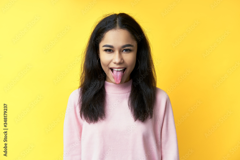 Pretty black woman showing tongue and looking at the camera on yellow background Pretty black woman showing tongue and looking at the camera on yellow background