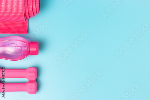 Sports mat  bottle of water and pink dumbbells on blue background  a copy of the space