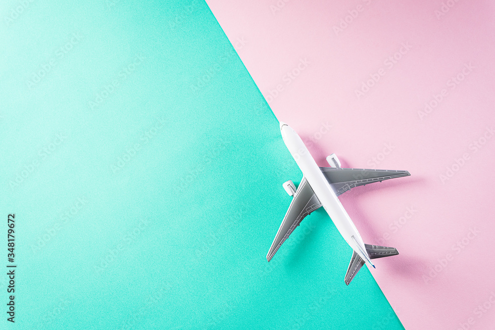 Summer holiday travel and vacation concept. Air plane on pastel green and pink background with copy space for text. Flat lay design.