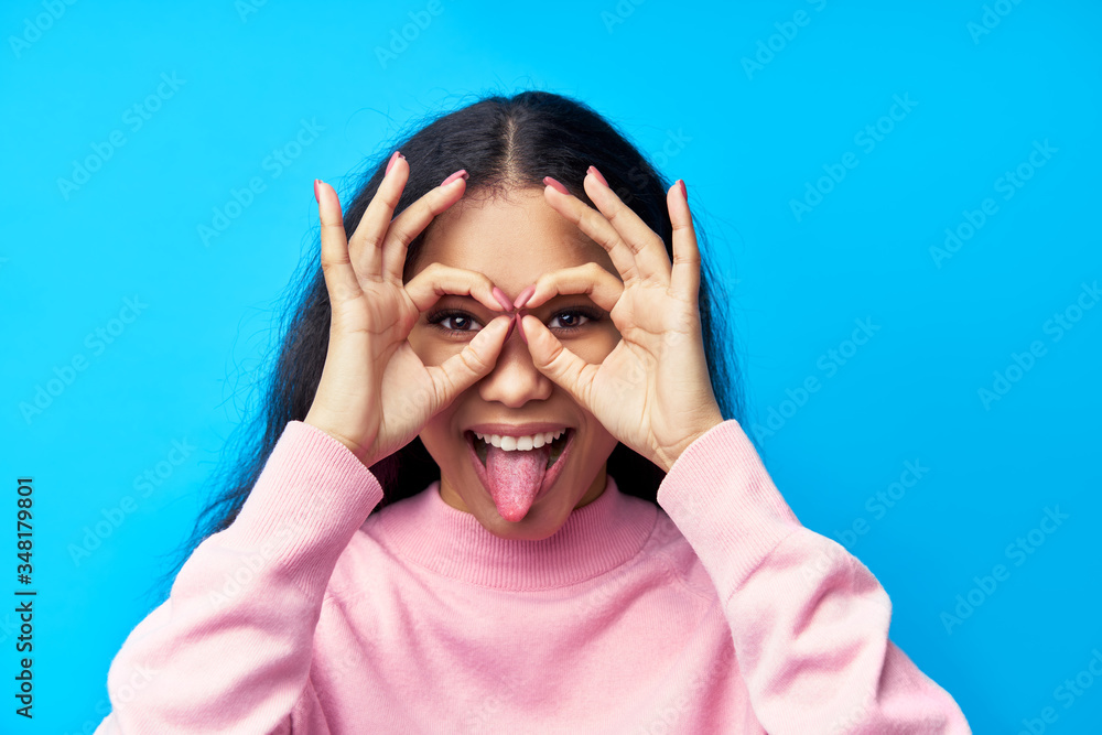 Funny black woman showing tongue and lmaking eyewear with fingers on blue background Funny black woman showing tongue and lmaking eyewear with fingers on blue background
