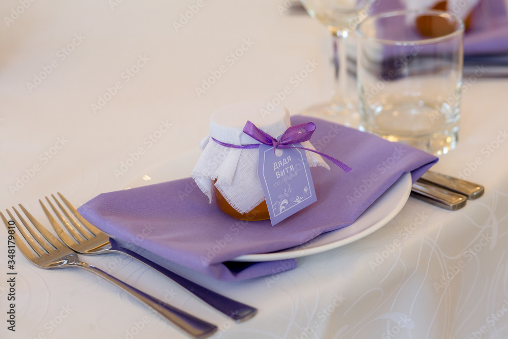 Wedding bonbonniere.A gift for guests is a jar of honey on a plate. wedding table setting. decor in the purple palette Wedding bonbonniere.A gift for guests is a jar of honey on a plate. wedding table setting. decor in the purple palette