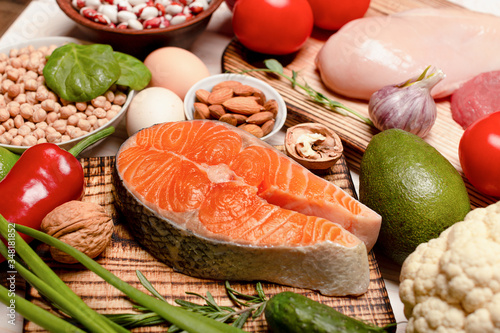 Raw salmon steak and ingredients for cooking on a wooden background, close up. Protein sources.