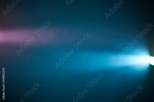 Against the background of volumetric light of a light blue ray, a short pink glow