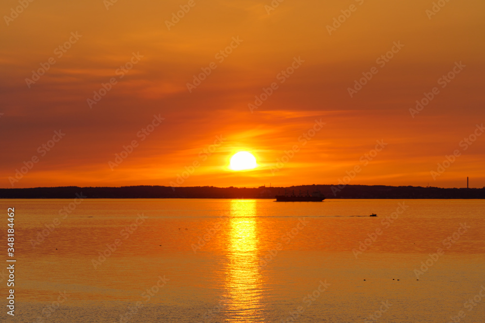 Golden sunset over the ocean with cargo ship in silhouette.