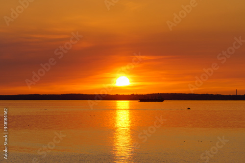 Golden sunset over the ocean with cargo ship in silhouette. © PhotosbyPatrick