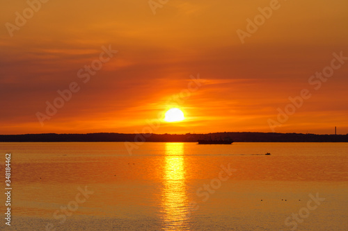 Golden sunset over the ocean with cargo ship in silhouette.