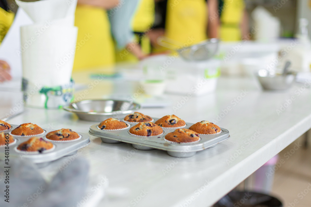 Confectioner took out freshly baked muffins in a baking dish on the table from the oven Confectioner took out freshly baked muffins in a baking dish on the table from the oven
