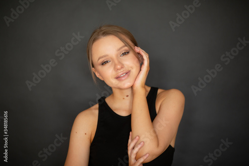 beautiful, lovely girl smiling at the camera on a dark background in the studio