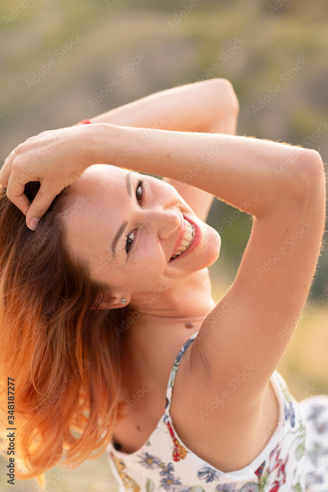 Tender beautiful red-haired girl enjoys the sunset in a field with a hill. Tender beautiful red-haired girl enjoys the sunset in a field with a hill.