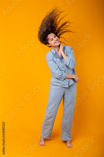 Young girl posing in pajamas on yellow background. Relax good mood, lifestyle and sleepwear concept. © satura_