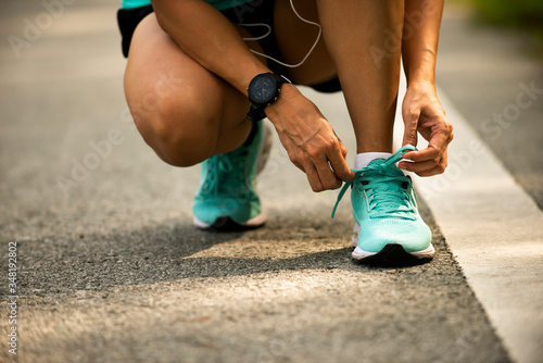 Close up on sporty woman  hands shoelace before jogging at park
