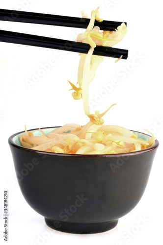 Bol de germes de soja avec des baguettes chinoises en gros plan sur fond blanc