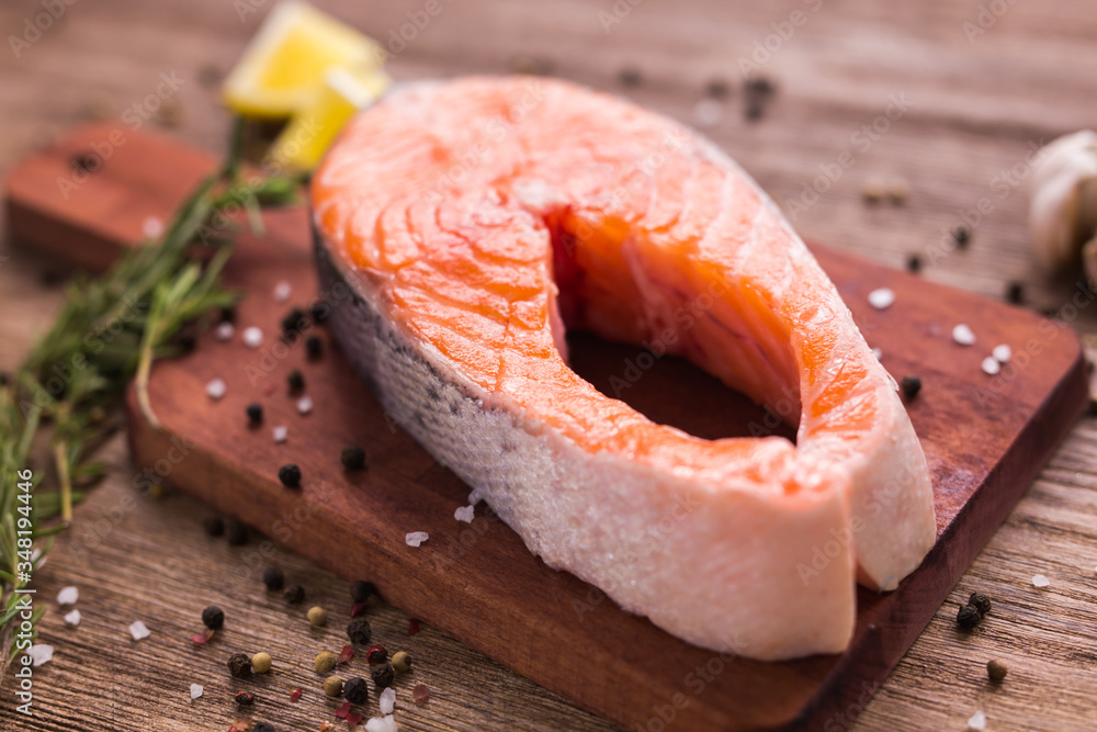 Raw salmon steak on wooden board. Healthy food, diet and mediterranean cuisine concept Raw salmon steak on wooden board. Healthy food, diet and mediterranean cuisine concept