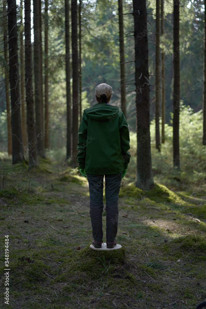 Fototapeta premium Unrecognizable man in a green plastic mask in the forest as a symbol.