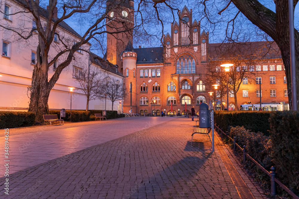 City hall clock tower street view evening of district Köpenick in Berlin, Germany empty park with street lights, benches and trees in foreground