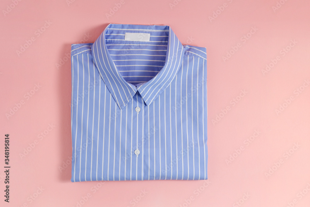 One perfectly folded buttoned shirt with striped pattern. Single piece of formal wear with blank label isolated on pink background. Close up, top view, copy space. - obrazy, fototapety, plakaty 