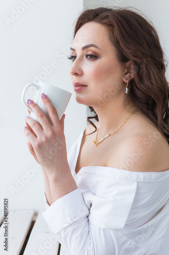 Close up of beautiful female hands holding big white cup of cappuccino coffee.