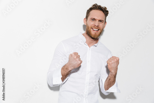 Image of handsome excited man making winner gesture and smiling