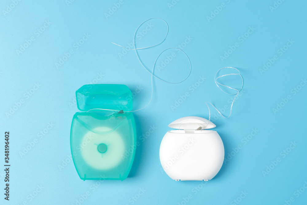 Dental floss containers on blue background. Daily oral hygiene, teeth