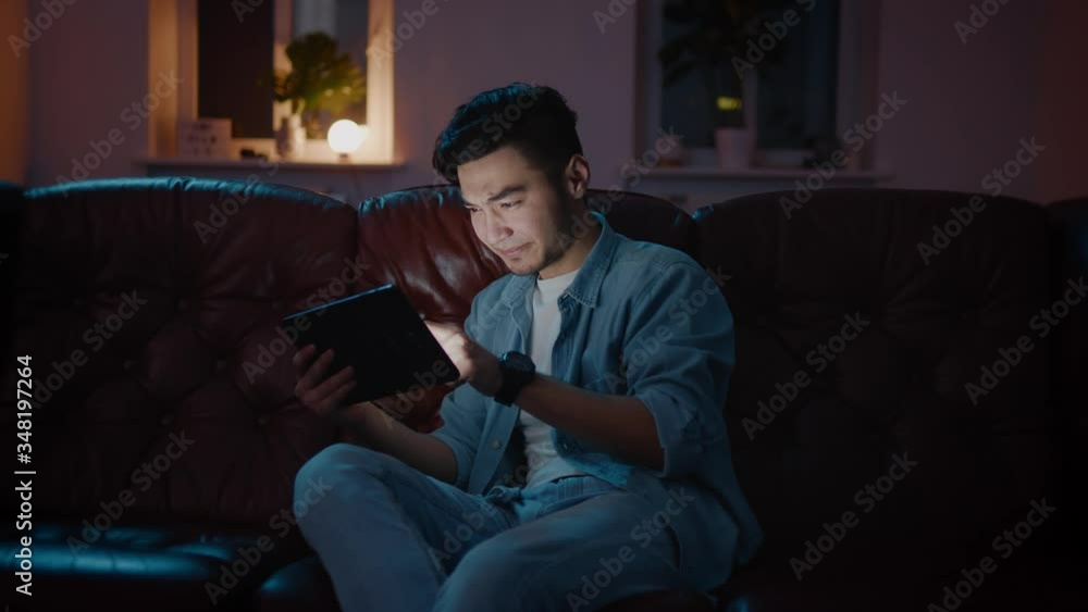Emotional Handsome Asian men wins on game on tablet and enjoy it. Emotional Handsome Asian men wins on game on tablet and enjoy it.