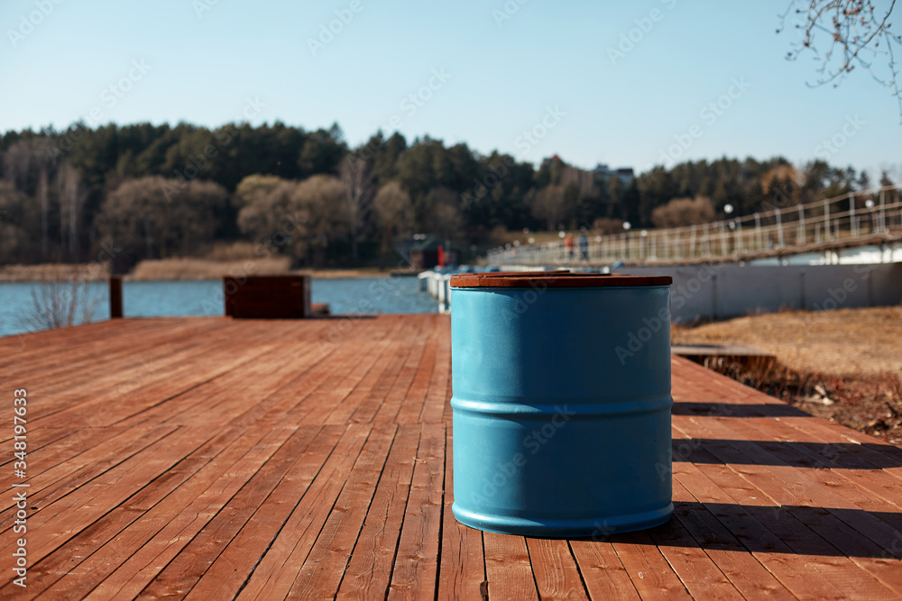 The blue barrel stands on the lake shore on a wooden pier. Spring landscape, blurred background The blue barrel stands on the lake shore on a wooden pier. Spring landscape, blurred background