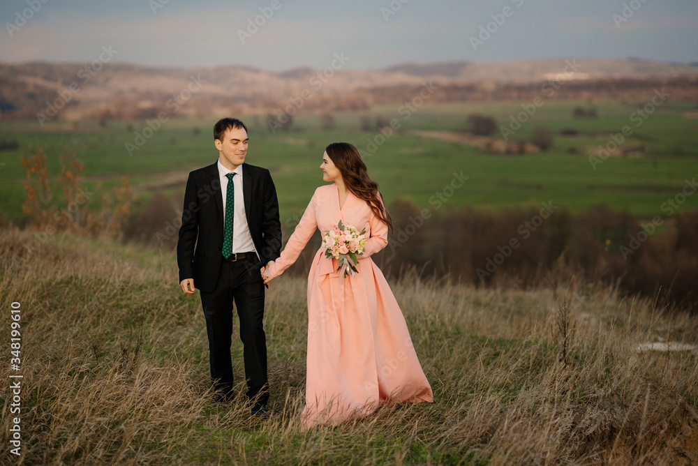 Happiness couple walk at wedding day, against the background of a beautiful view of nature at sunset