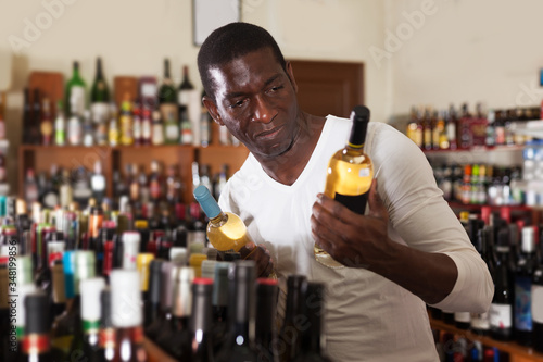 Afro man choosing bottle of wine