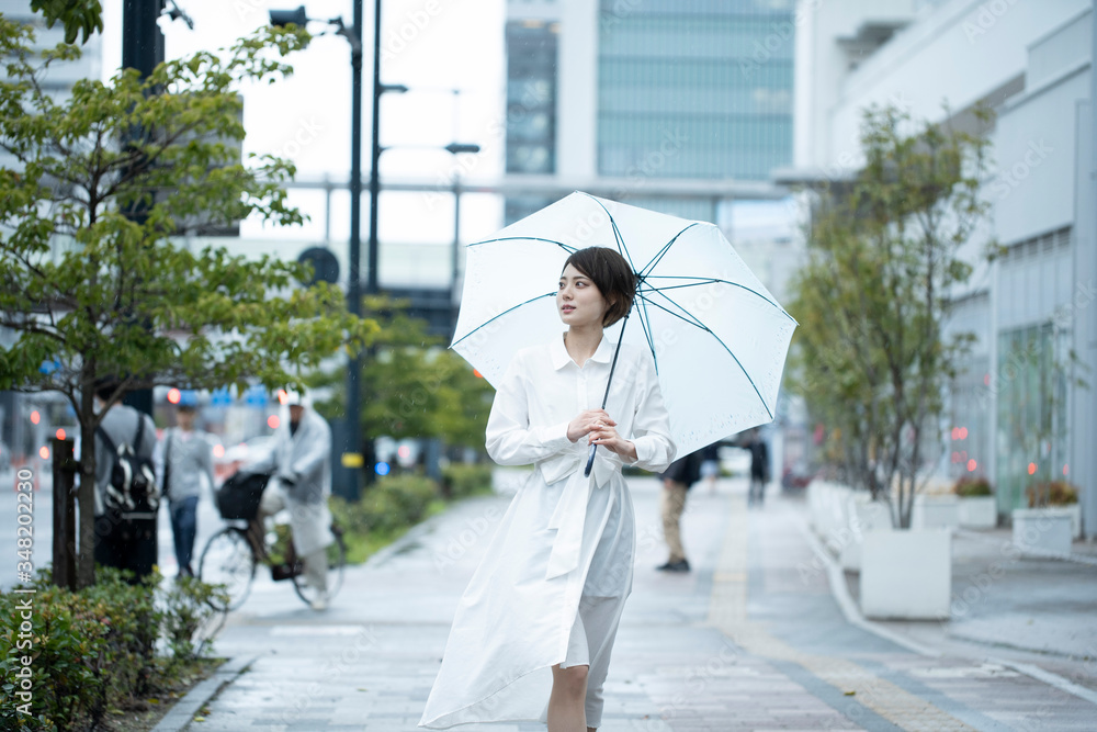 雨の中傘をさして歩く白いワンピースを着た若い女性 Stock Foto Adobe Stock 雨の中傘をさして歩く白いワンピースを着た若い女性 Stock Foto Adobe Stock