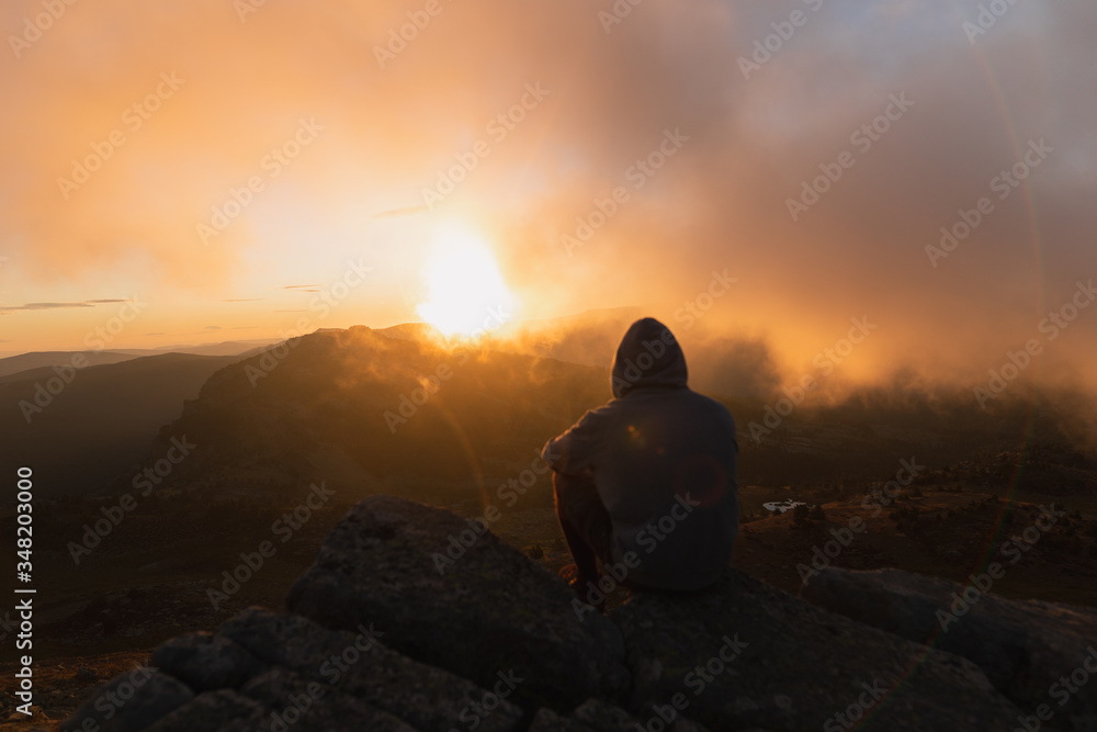 Man standing and watching a colorful sunrise in the mountains.