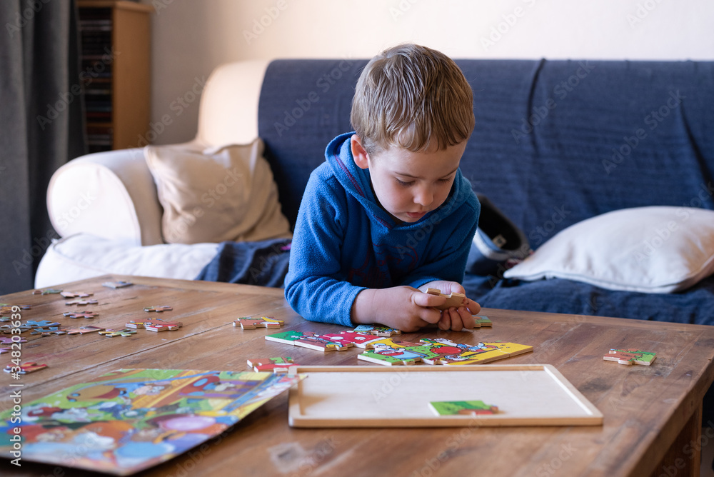 A 3 year old boy doing a puzzle at home, in the living room, during the Corona Virus, while being homeschooled. A 3 year old boy doing a puzzle at home, in the living room, during the Corona Virus, while being homeschooled.