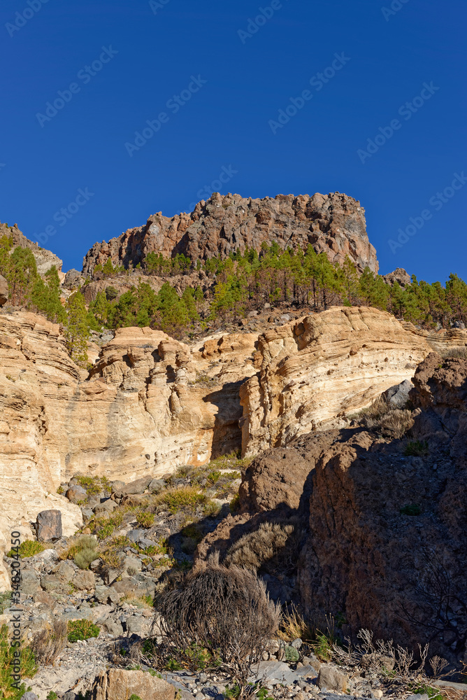 A Volcanic Plug geological feature above the steep Hillside and gorge within Tiede National Park, with its lava flows and different rock layers visible.