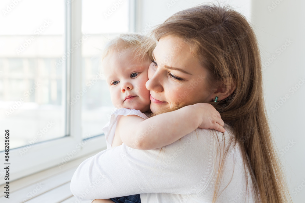 Young mother playing with her baby girl at home. Motherhood, infant and children concept.