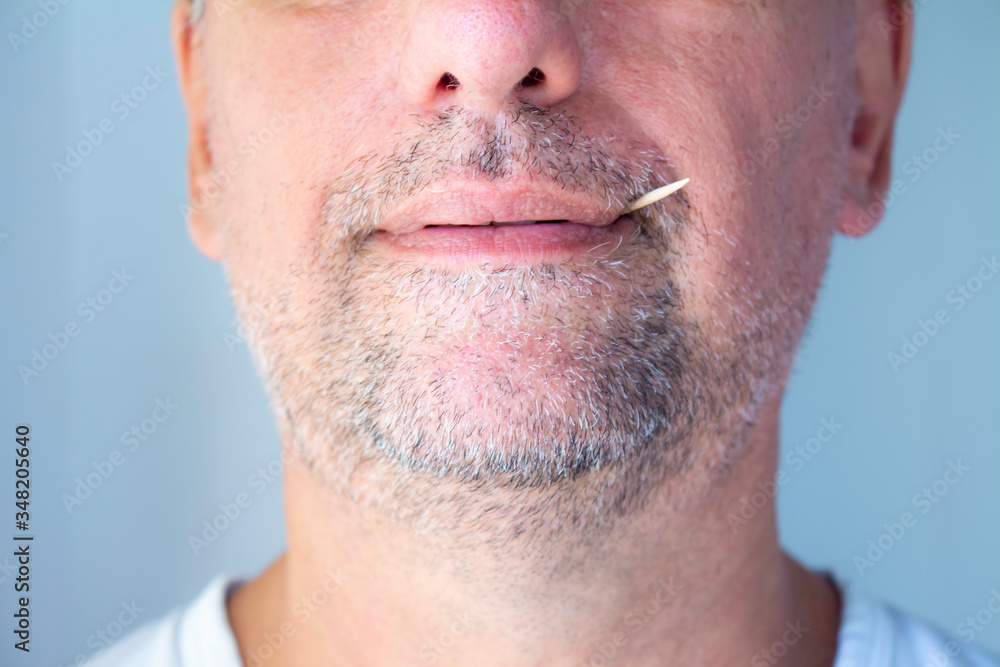 Obraz premium White man with toothpicks in his mouth. Grinning grin with barely grown gray beard