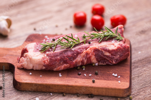 Fresh raw meat for steak on wooden cutting board.
