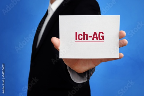 Ich-AG. Anwalt hält Karte in der Hand. Beschriftung auf Schild zeigt Begriff. Hintergrund blau. Recht, Gesetz, Rechtsprechung