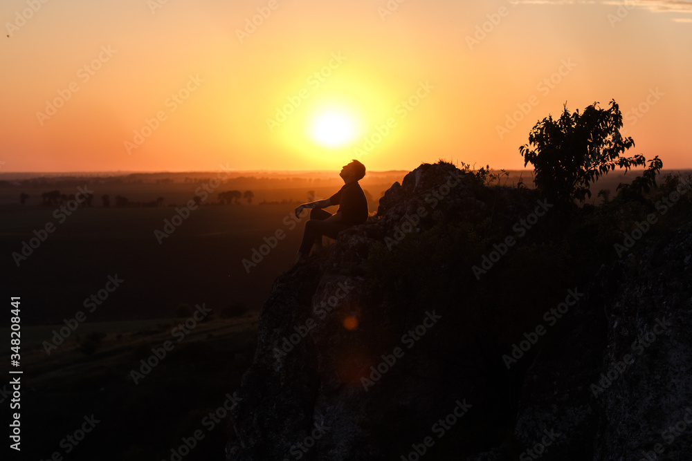 Silhouette of a man sitting on a rock and watching in the distance. Silhouette of a man sitting on a rock and watching in the distance.