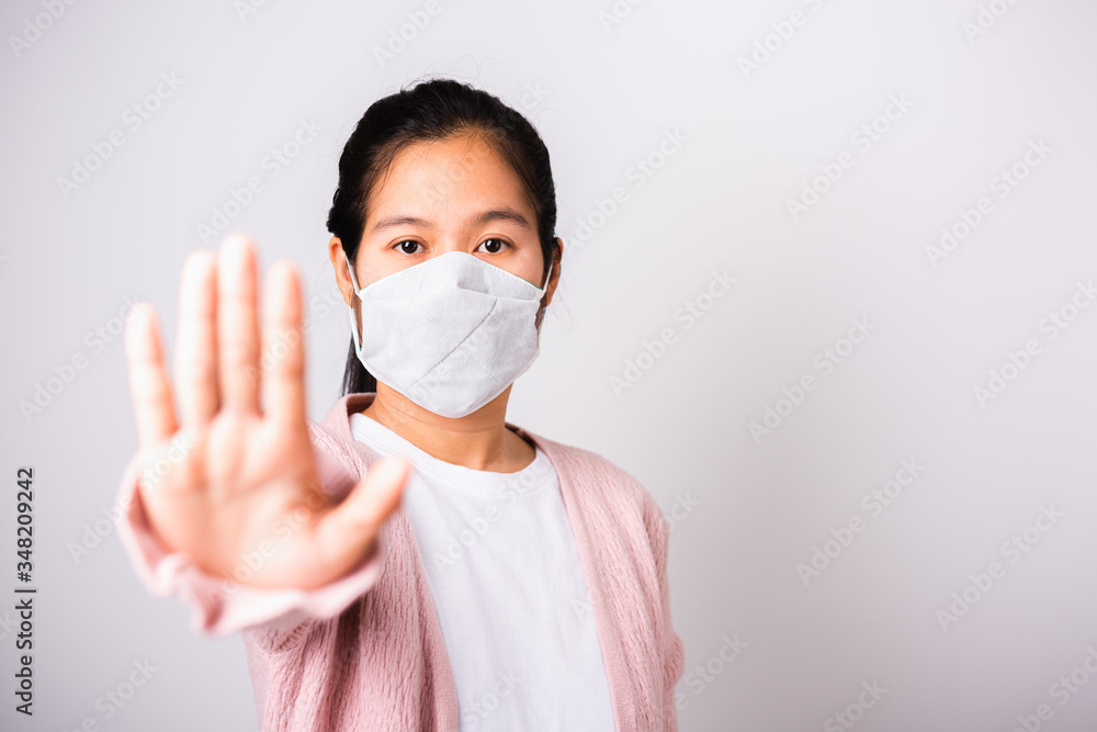Asian woman wearing surgical protection face mask hygiene against coronavirus her raising hand stop sign, studio shot isolated on white background with copy space, COVID-19 or corona virus concept Asian woman wearing surgical protection face mask hygiene against coronavirus her raising hand stop sign, studio shot isolated on white background with copy space, COVID-19 or corona virus concept
