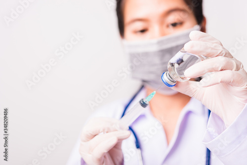 Closeup female woman doctor  nurse or scientist in uniform wearing face mask protective in lab use holding and syringe injecting to vial vaccine bottle  medical outbreak coronavirus COVID-19 concept