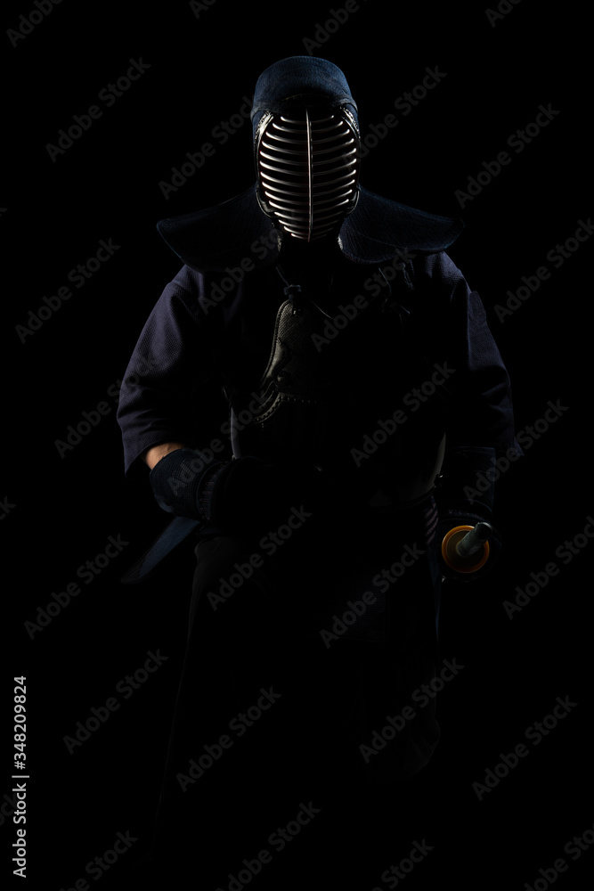 Naklejka premium male in tradition kendo armor with shinai (bamboo sword). shot in studio. Isolated with clipping path on black background