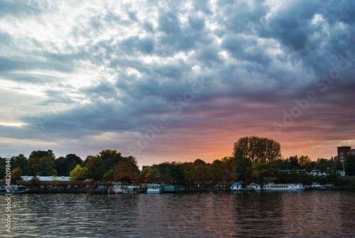 Sunset on the embankment of the river Spree in Berlin, Germany. Beautiful clouds and sunset light over the trees.