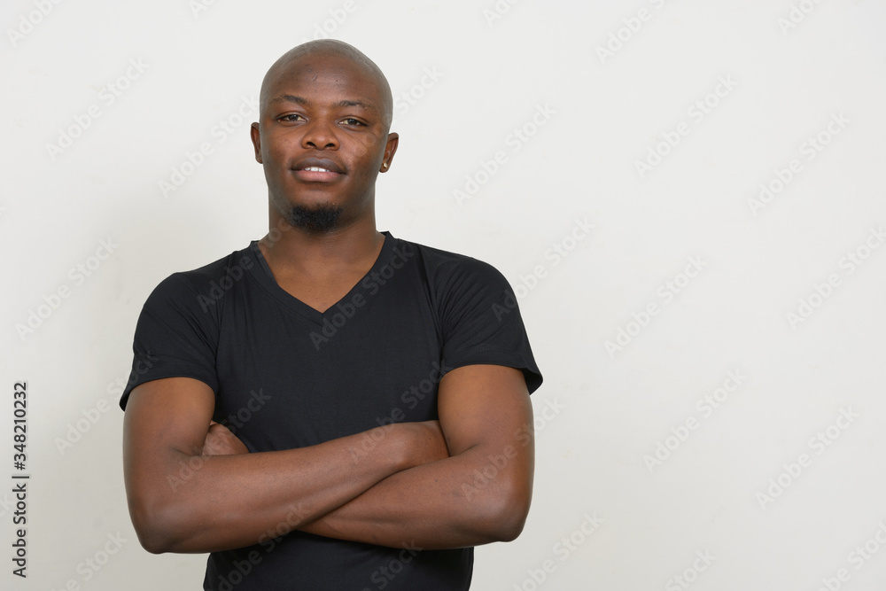 Happy young handsome bald African man smiling with arms crossed Happy young handsome bald African man smiling with arms crossed